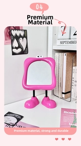 Close-up of pink cartoon vanity mirror with cute eye decor and feet base on desk