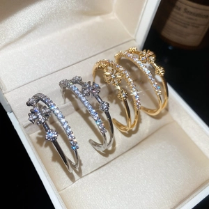 Vue détaillée des boucles d'oreilles fleur en C plaquées or 18k avec du zircon