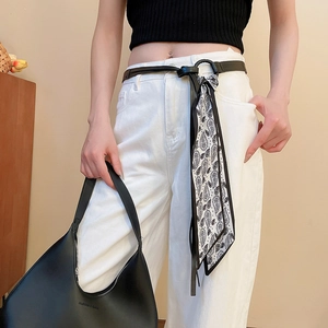 Detail of leather belt with vintage floral scarf charm and black half-moon bag
