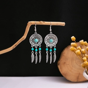 Detailed macro view of bohemian dreamcatcher earrings with turquoise beads on wood
