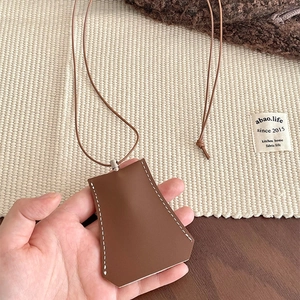 Detail of a brown leather clochette key case with white contrast stitching and silver hardware
