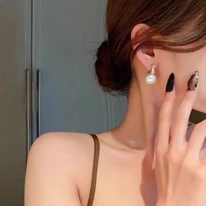 Close-up of elegant pearl drop earrings with sparkling diamond-set gold hoops on model
