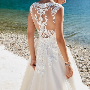 Lace bridal gown with open back, floral embroidery, and buttons for a beach wedding