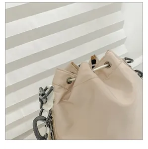 Detail of cream nylon bucket bag showing drawstring closure and reinforced metal eyelets
