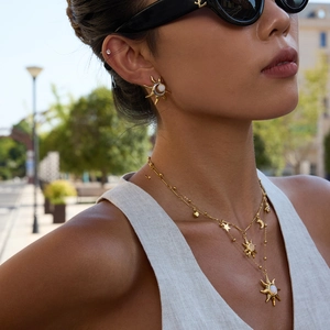 Detail of model wearing celestial sun and moon pendant necklace and stud earrings