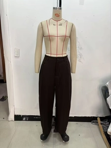 Close-up of high-waisted dark brown casual trousers on a mannequin with single button zip fly