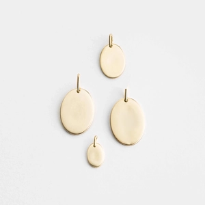 Detailed view of four polished gold stainless steel oval pendants with ring loops