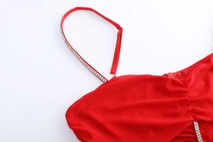 Gros plan sur une robe rouge froncée avec des bretelles fines ornées de strass brillants