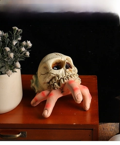 Close-up of a skull seashell decoration held by resin hands with red blood tips