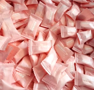 Pile of portable pink compressed facial towels in individual packaging for travel