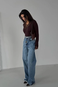 Detail of dark brown lace V-neck long sleeve top styled with blue wide leg jeans