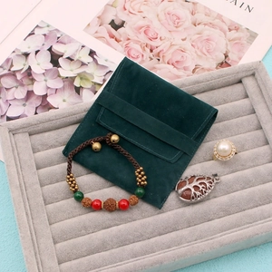 Detail of dark green velvet jewelry pouch with pearl ring and beaded bracelet set