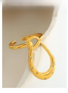 Detail view of a gold-plated geometric knot ring featuring micro-pave cubic zirconia accents