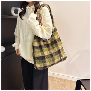 Detail shot of a green and black checkered plush tote bag shown over the shoulder on a model