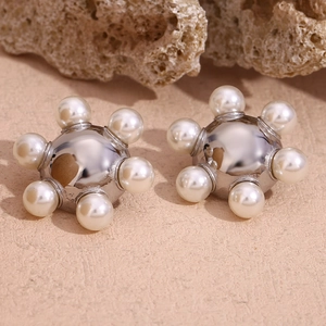 Detailed macro view of silver sphere earrings surrounded by pearls on natural stone