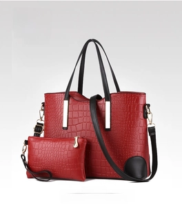 Detail of wine red croc-embossed tote bag and matching clutch set with gold hardware