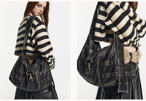 Detail of black leather hobo bag with vintage texture and metallic buckle strap accents