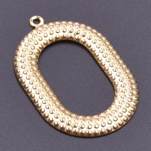 Detailed macro view of gold-plated oval metal pendant with textured grain finish