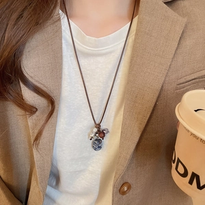 Close-up of ethnic beaded necklace featuring a textured blue-grey stone pendant on wax cord