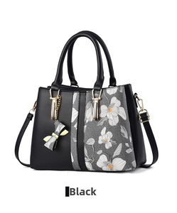 Detail of black tote bag with white floral pattern and gold-tone hardware accents