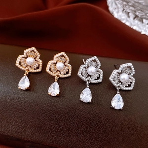 Macro detail of luxury flower drop earrings with pearls and crystals on leather surface