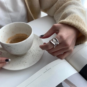 Close-up of wide irregular 925 silver ring worn by a model holding a coffee cup