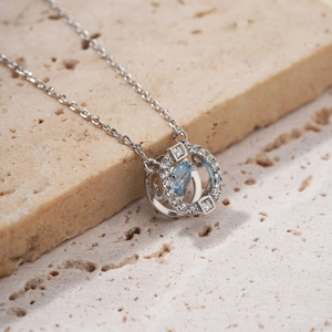 Silver necklace with light blue waterdrop pendant and stones on beige stone base