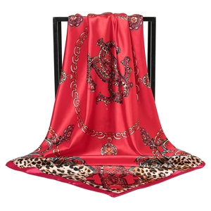 Red silk square scarf featuring leopard print borders and decorative golden chain motifs
