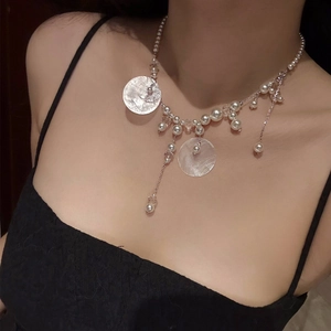 Close-up of shell pendant necklace with pearls and crystals on a model's collarbone