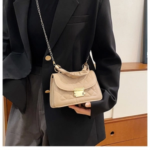 Detalle de bolso acolchado caqui con cadena dorada y asa con textura de cuero fino