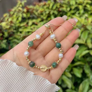 Detail of 18k gold-plated beaded bracelet with virgin mary coin charm on woman's wrist