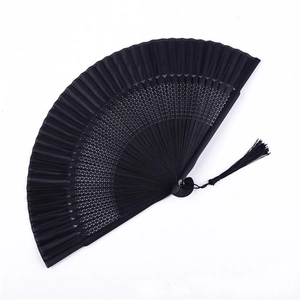 Close-up of black lacquered folding fan with elegant hollow-out bamboo ribs and matching tassel