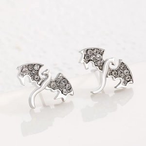 Vue macro des boucles d'oreilles dragon argentées avec strass brillants et ailes punk