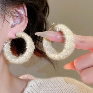 Nahaufnahme beiger Strick-Creolen mit Goldschließe am Model für den Winter-Look