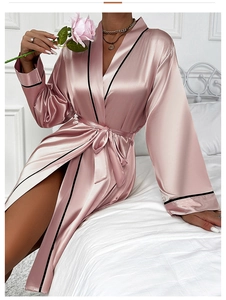 Detail view of pink satin robe showing black contrast piping and silky texture on sleeves