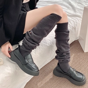 Close-up of dark grey ribbed knit over-the-knee socks paired with black platform loafers