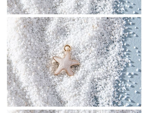 Detail of star-shaped enamel jewelry charm on white sand background for DIY designs