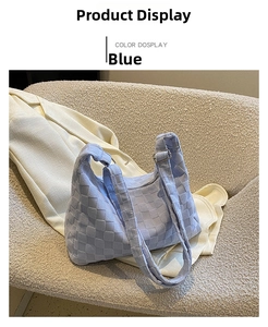 Detailed view of blue woven hobo bag with wide leather straps on a beige chair