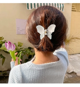 Detail of translucent white butterfly hair claw clip worn in a half-up hairstyle