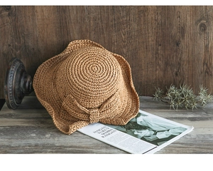 Detalle de sombrero de paja tejido a mano con lazo grande sobre fondo de madera vintage