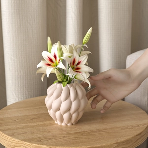 Dettaglio del vaso minimalista in ceramica rosa con trama intrecciata e gigli bianchi