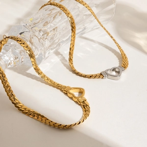 Close-up of gold and silver heart necklaces on glass in soft light background