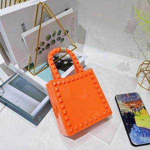 Detailed view of orange PVC jelly mini bag featuring signature metal stud trim accents