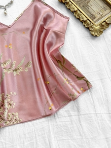 Détail d'un caraco en satin rose à fleurs sur fond de tissu blanc texturé plissé