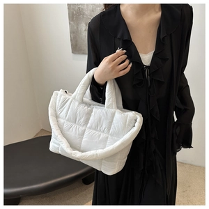 Detailed close-up of a white quilted crossbody bag worn over a black elegant dress