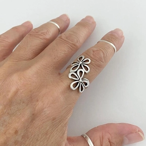 Minimalist silver open ring with double flower design worn on hand with multiple bands