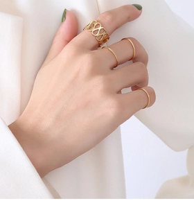 Close-up of minimalist gold titanium steel ring set on model's hand showing four pieces