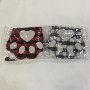 Detail of red and black buffalo plaid Christmas dog paw stockings in plastic packaging