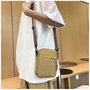 Detail view of a compact yellow canvas crossbody bag featuring a front zipper pocket