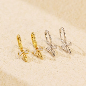 Macro shot of s925 silver bow earrings with sparkling stones in gold and silver finish